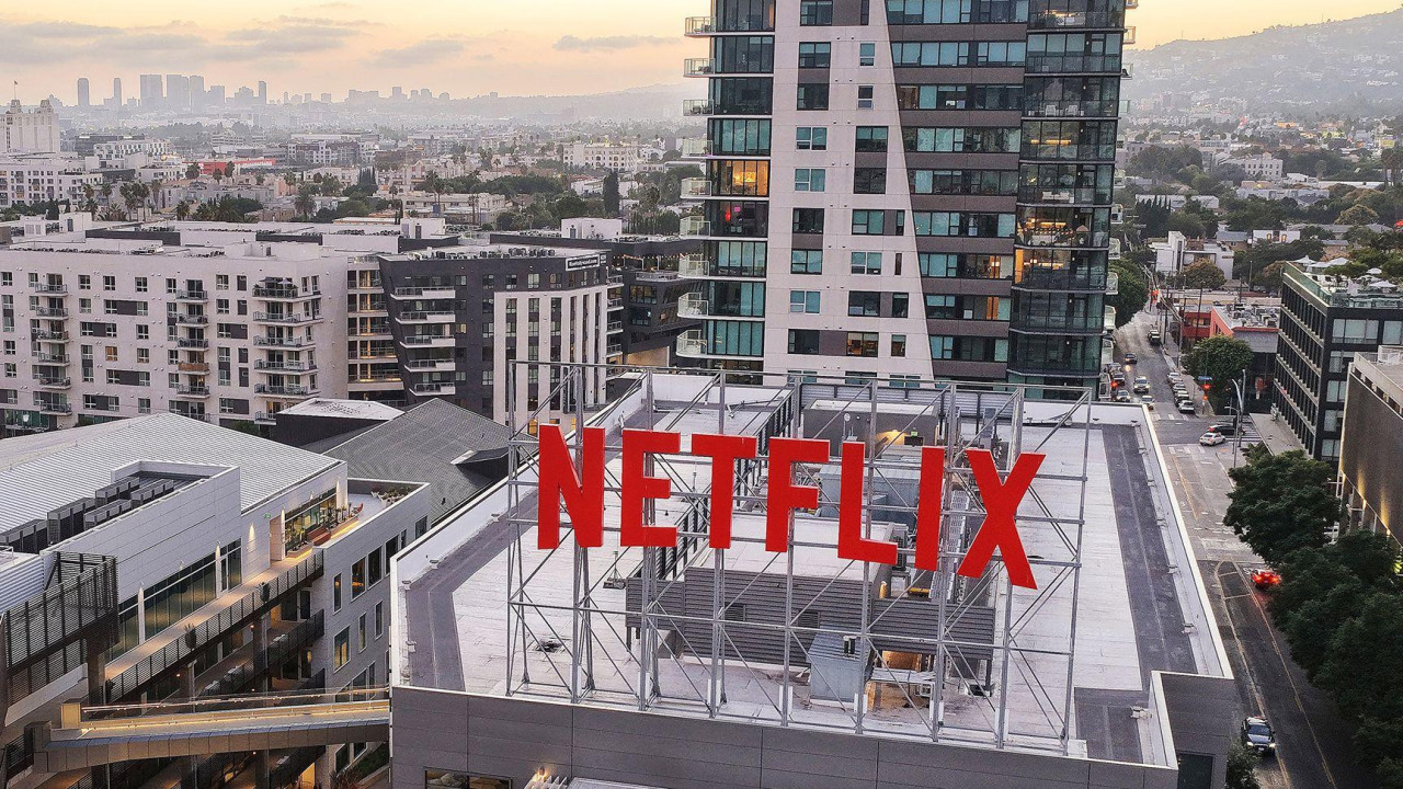 The roof of the Netflix offices in Los Angeles with large red NETFLIX  sign in foreground and city scape in the background