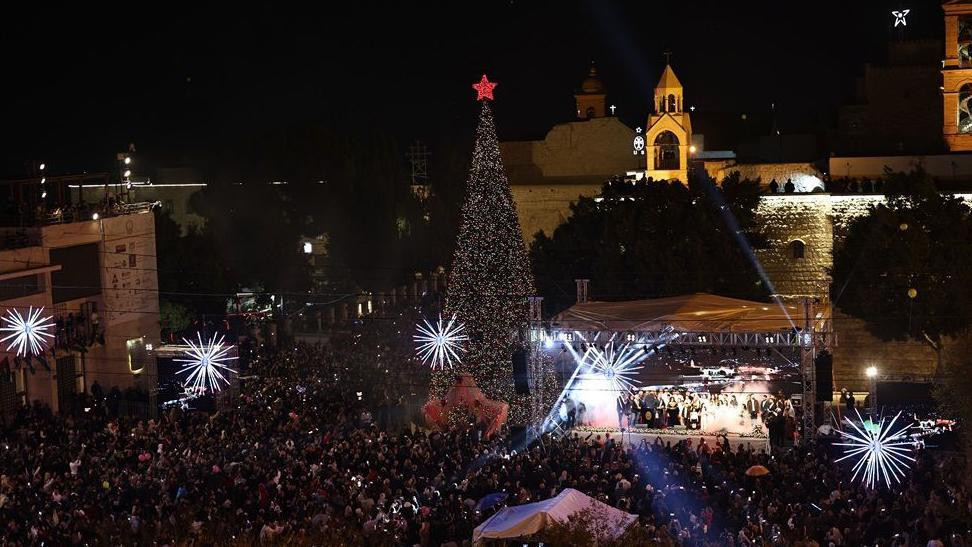 Vitlejem noćni pogled na osvetljeni trg sa velikom jelkom i crvenom zvezdom na vrhu