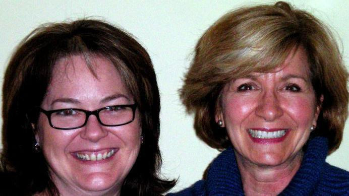 dve žene se smeju u kameru, jedna nosi naočare