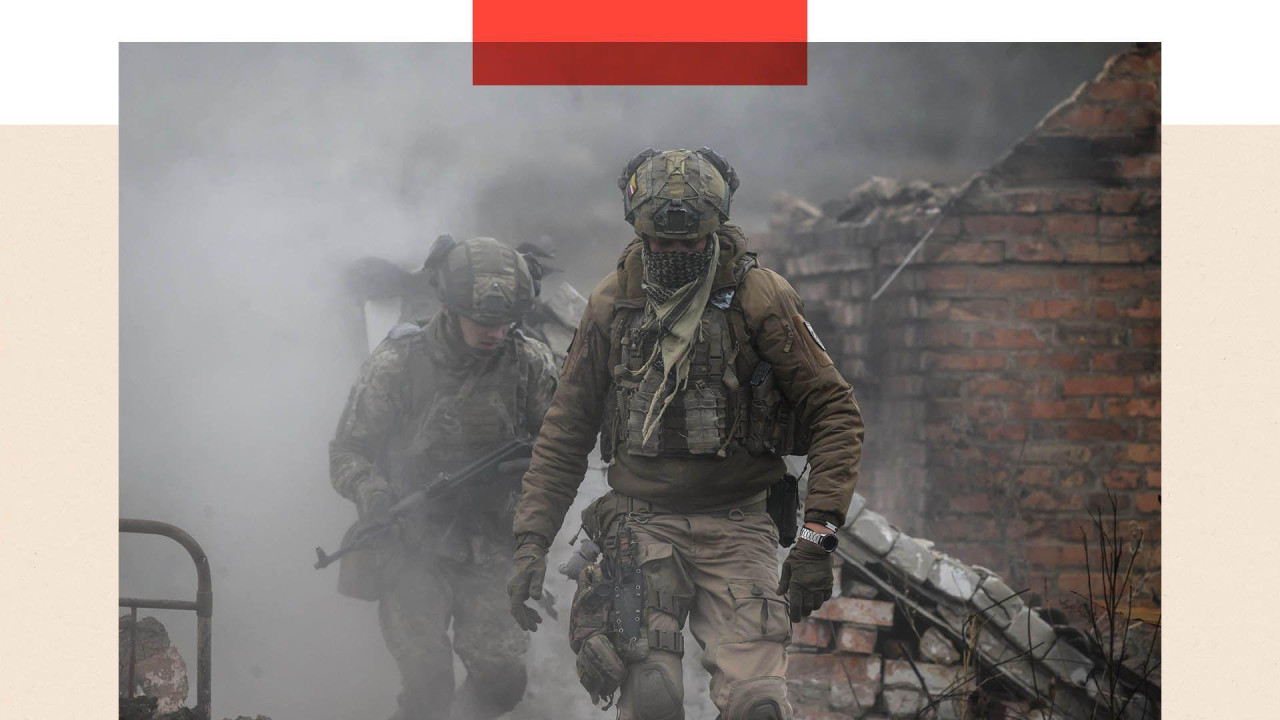 Dva vojnika u punoj opremi, iza njih su ruševine  