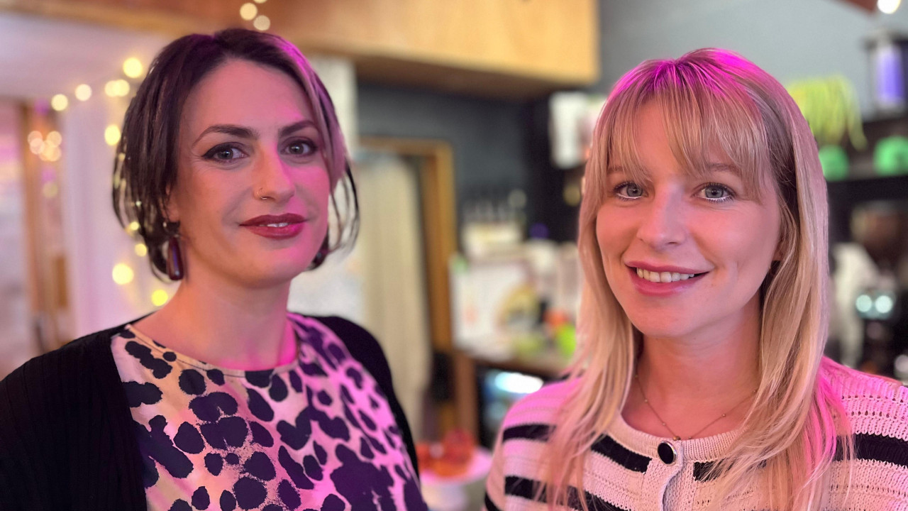 Madlen Tomas i Džes Dejvis u kafiću osmehuju se gledajući u kameru