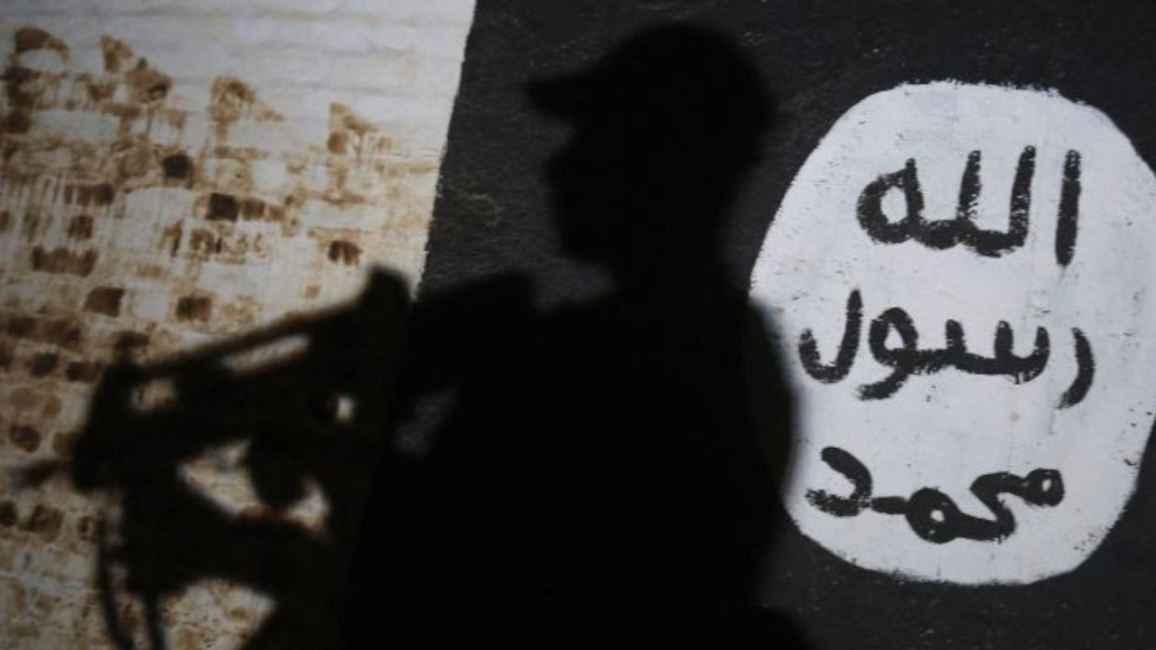 
                    A member of the Iraqi forces walks past a mural bearing the logo of the Islamic State (IS) group during a 2017 operation near Mosul. We can only see his shadowy presence 