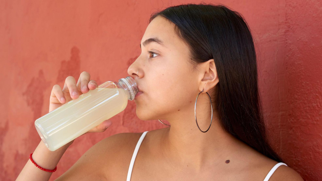 Mlada žena pije osvežavajuće piće iz plastične flaše 