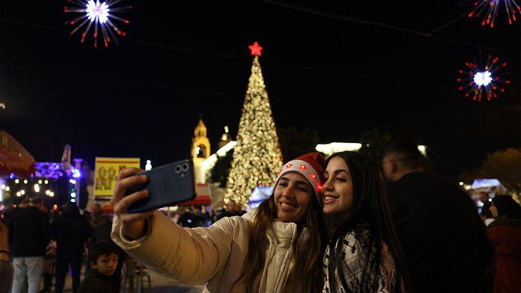 Dve žene prave selfi ispred novogodišnje jelke u Vitlejemu, gradu u okupiranoj Zapadnoj Obali, za koji se veruje da je mesto rođenja Isusa Hrista
