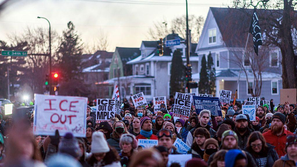 Ljudi demonstriraju protiv ICE-a tokom bdenja za Rene Gud, koju je ubio imigracioni agent. Nose transparent na kojima piše 'ICE napolje'
