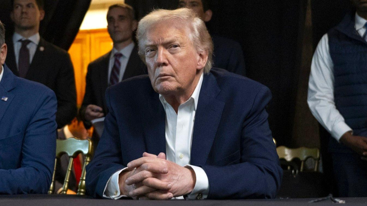 Donald Tramp u plavom sakou sedi prekrštenih ruku