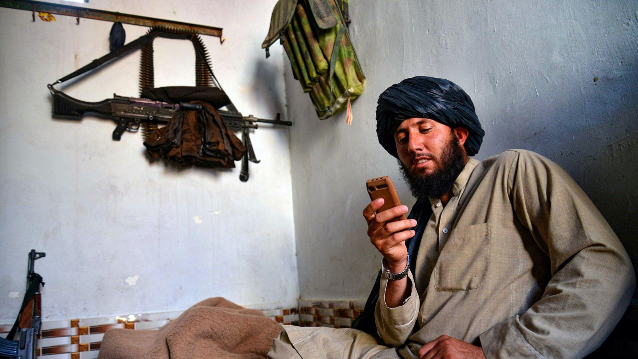 Talibanski pripadnik obezbeđenja gleda u telefon