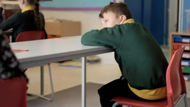 dečak sedi u učionici i zamišljeno gleda