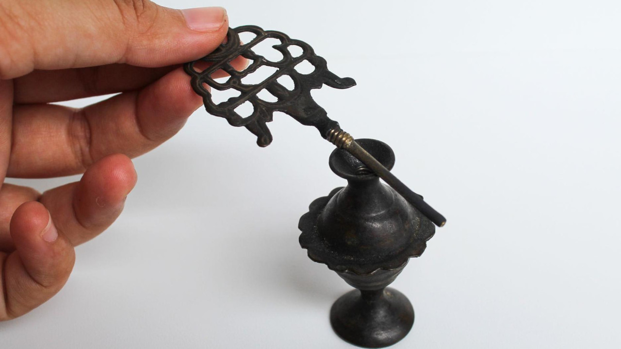 Ženska ruka u krupnom kadru drži antički pribor za nanošenje kajala i  women's hand holding an old make up tool for Kohl eyeliner, and an old storage cup.