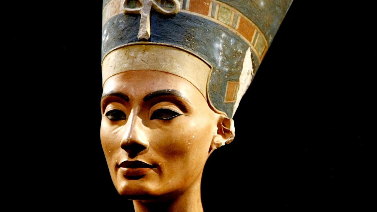 Glava kao deo biste skulpture egipatske faraonke Nefertiti na crnoj pozadini. Nefertiti ima iscrtan crni ajlajner 