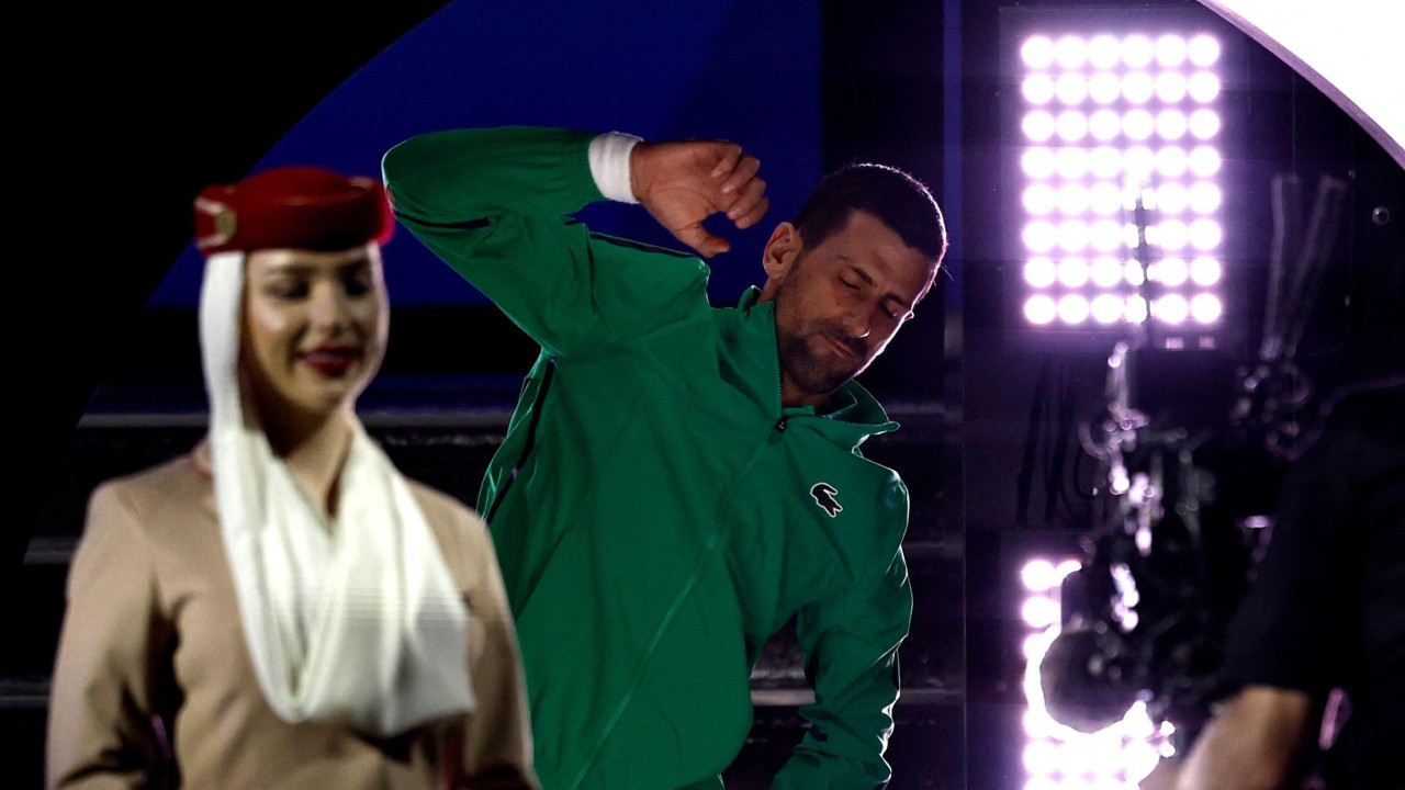 novak đoković se zagreva pred meč na australijan openu, ispred njega je devojka obučena kao stjuardesa neke arapske avio-kompanije