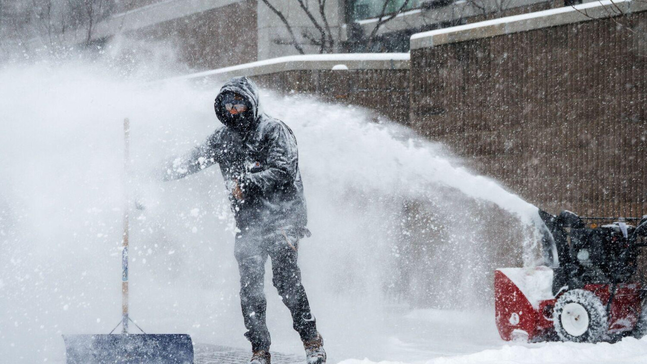 Muškarac čisti sneg ispred zgrade 