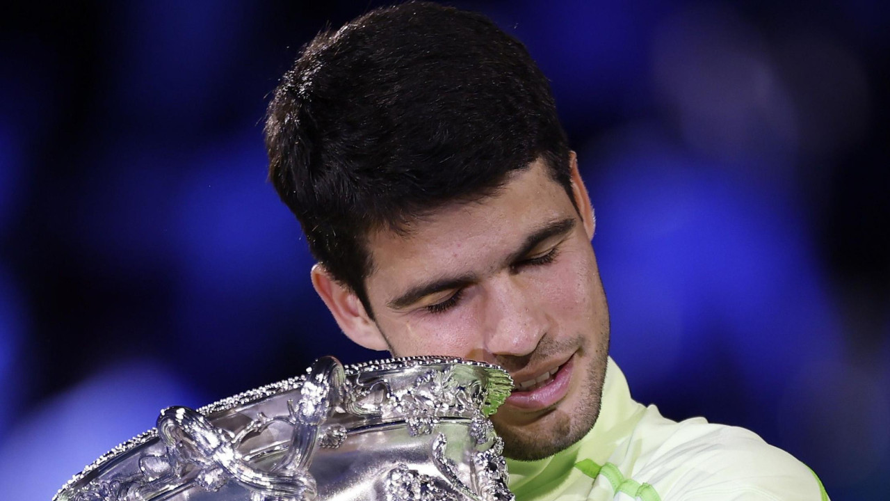 Carlos Alcaraz hugs the Australian Open trophy