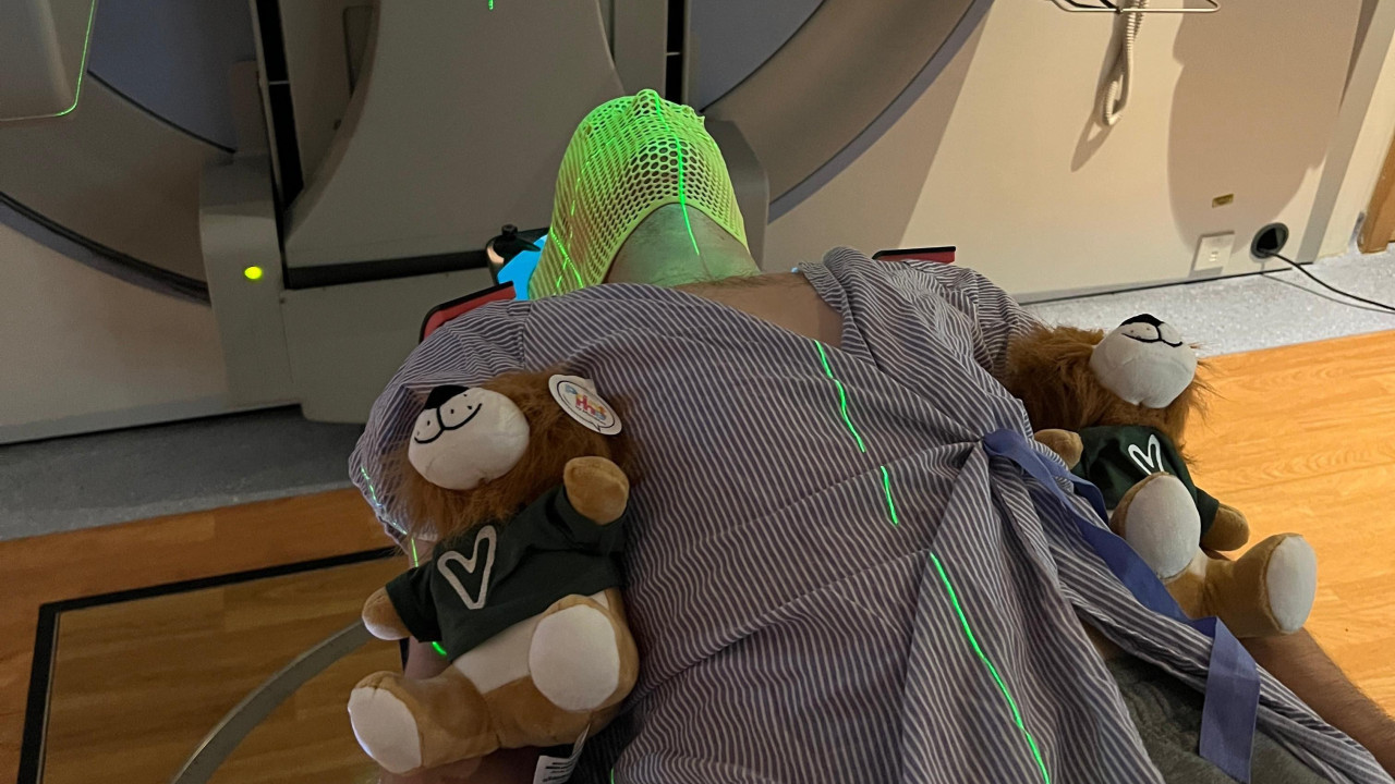 muškarac leži u bolničkoj krevetu sa dva plišana medvedića pored sebe. Nosi masku pre nego što će proći kroz skenir da bi se utvrdilo da li ima rak