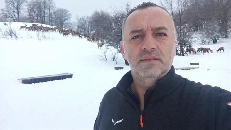 rendžer Laze u prvom planu, nosi crnu duksericu, u pozadini su jeleni i drveće bez lišća 