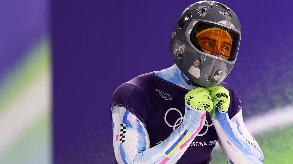 Mladić u zimskom sportskom odelu sa kacigom na glavi na kojoj su slike žrtava rata u Ukrajini