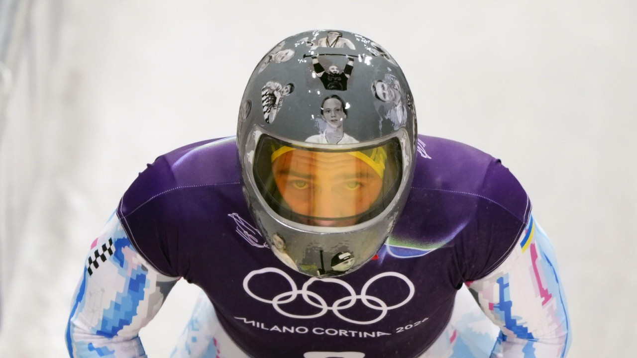Vladislav Geraskevič nosi kacigu sa slikama poginulih u ratu u Ukrajini na stazi za skeleton u Kortini, u Italiji, na Zimskim olimpijskim igrama
