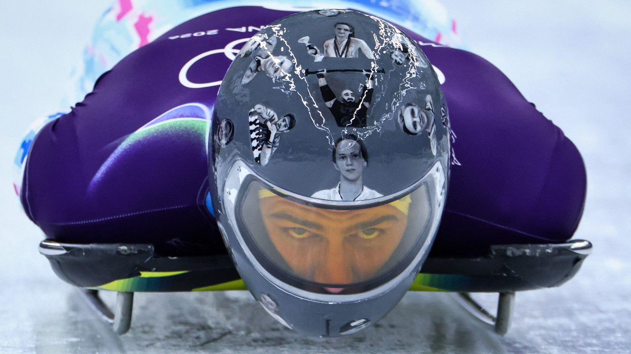 Vladislav Geraskevič nosi kacigu sa slikama poginulih u ratu u Ukrajini na stazi za skeleton u Kortini, u Italiji, na Zimskim olimpijskim igrama