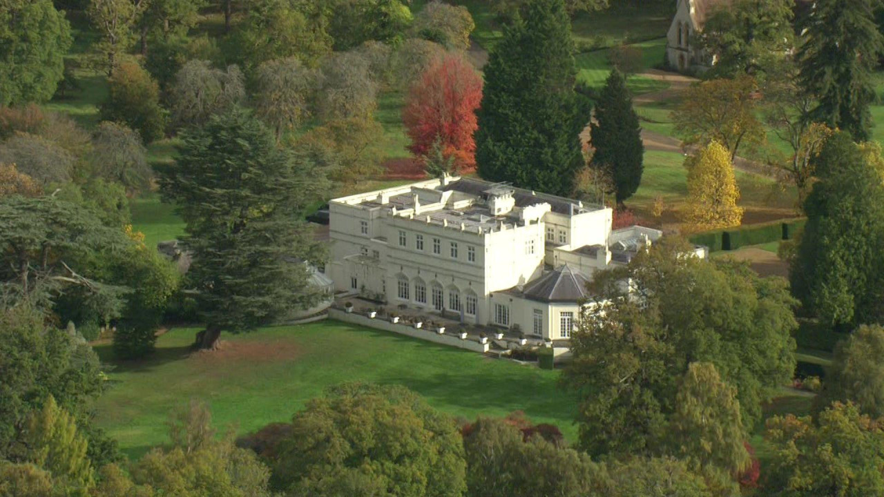 The Royal Lodge viewed from the air on 21 October 2025. It is a large rectangular white building with a lower atrium attached, set in luscious grounds. Some trees have brown leaves while others are green as the seasons turn from summer to autumn.