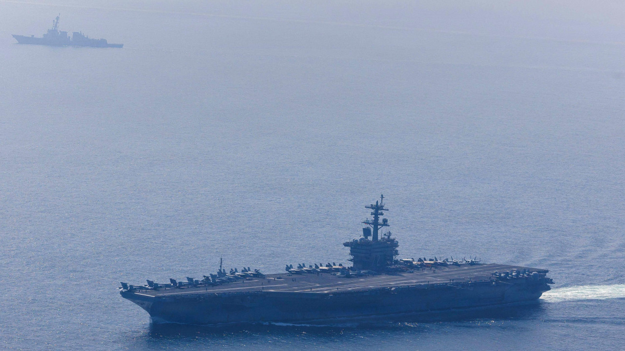Američki brod „Abraham Linkoln“ plovi na dnu slike 6. februara 2026. godine. To je veliki nosač aviona sa ravnom pistom. Više vojnih aviona je nepomično na drugoj strani broda. Mnogo manji američki brod „Frenk E. Petersen mlađi“ plovi na vrhu slike. Izvor: Američka mornarica / Specijalista za masovne komunikacije 1. klase Džesi Monford / Handout via Reuters