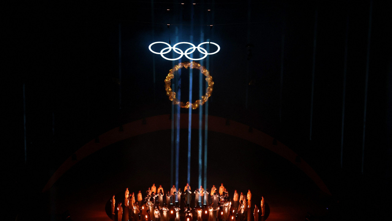 Grupa ljudi u krugu, u smeđim svetlima, iznad njih olimpijski krugovi