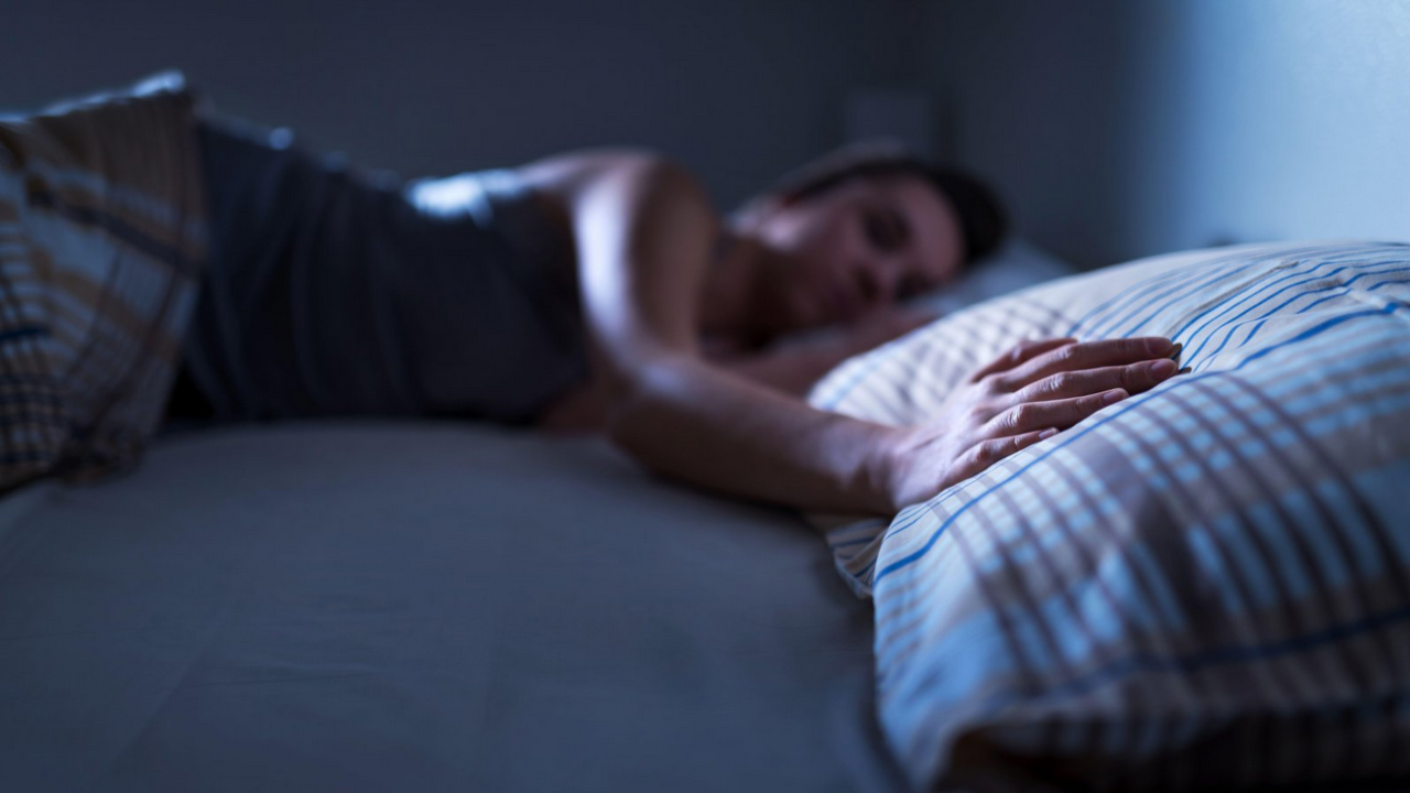 Žena u krevetu drži ruku na jastuku