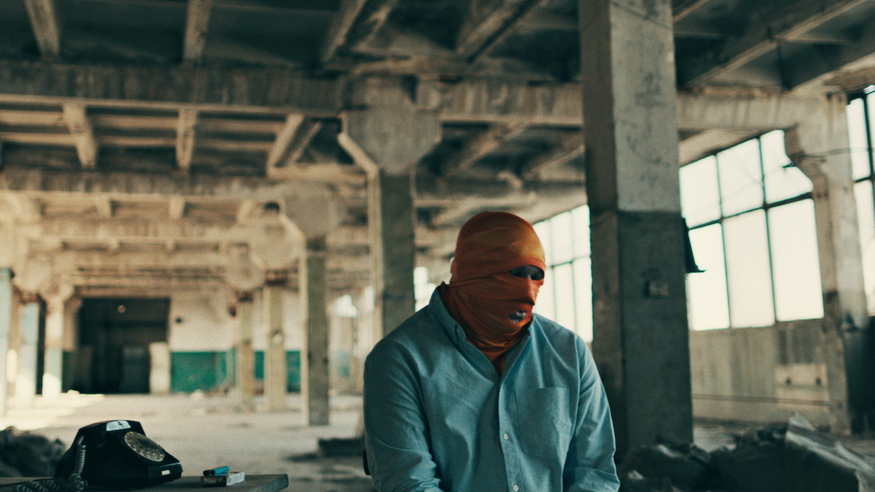 Bivši oficir ruske vojske, čije ime nismo objavili, sedi u skladištu, glava i lice su mu prekriveni narandžastom maramom