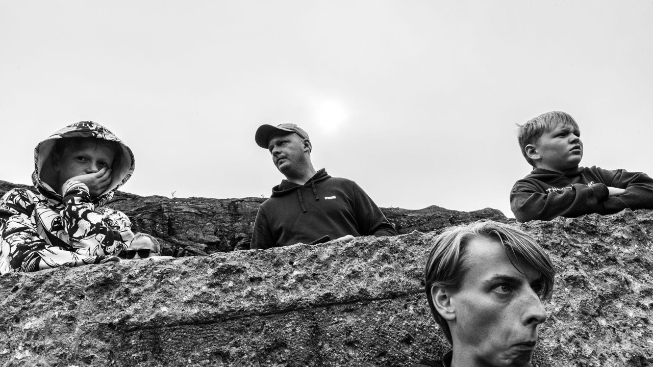 Crno-bela fotografija prikazuje četiri člana porodice, na različitim visinama duž nagiba, kako prave smešne grimase.