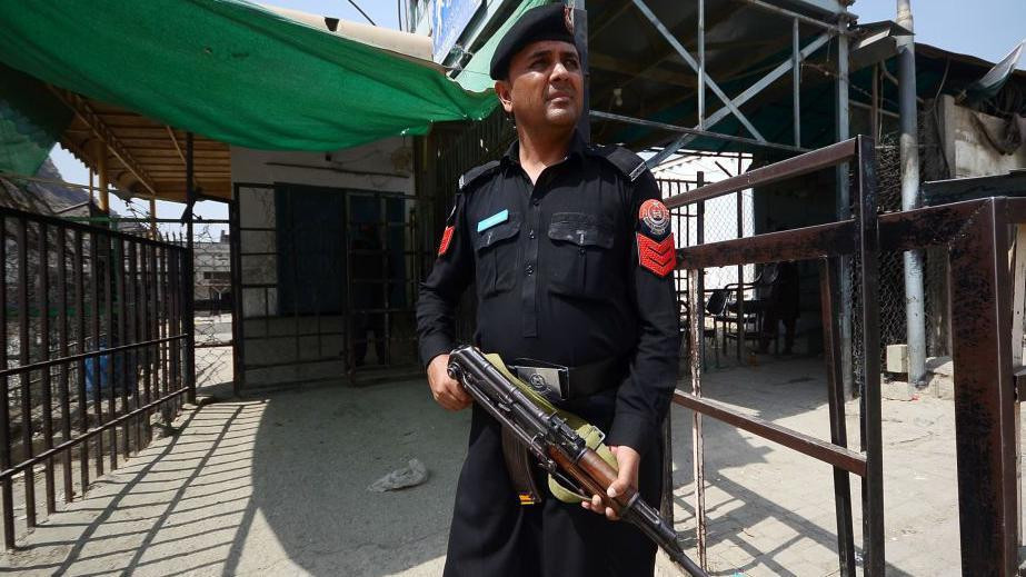 Pripadnik pakistanskih snaga bezbednosti u tamnoj uniformi drži automatsku pušku tipa AK74 na kontrolnom punktu