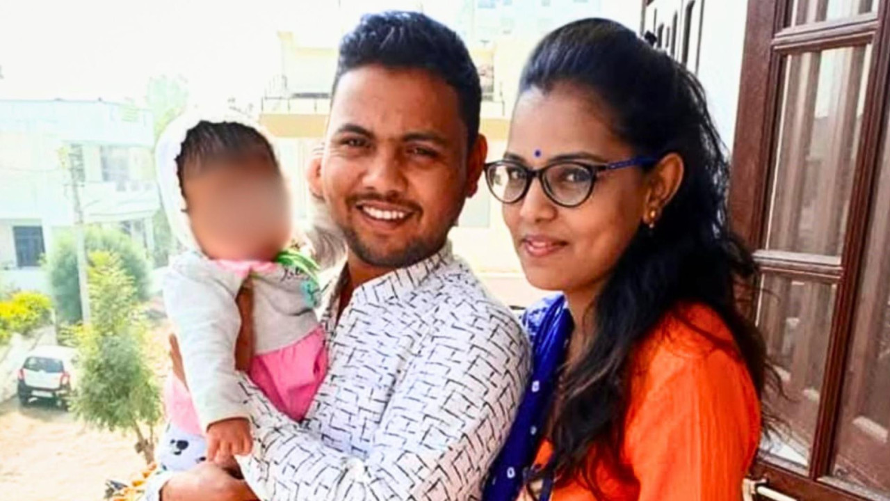 The couple with their baby daughter standing in front of a window at home