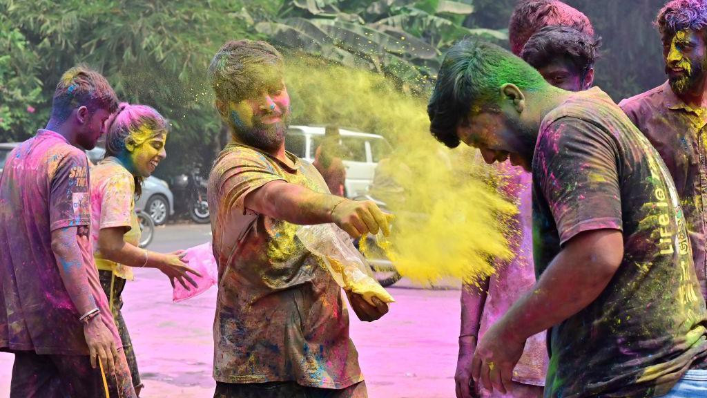 Nekoliko momaka bacaju jedni na druge obojeni prah tokom proslave festivala Holi