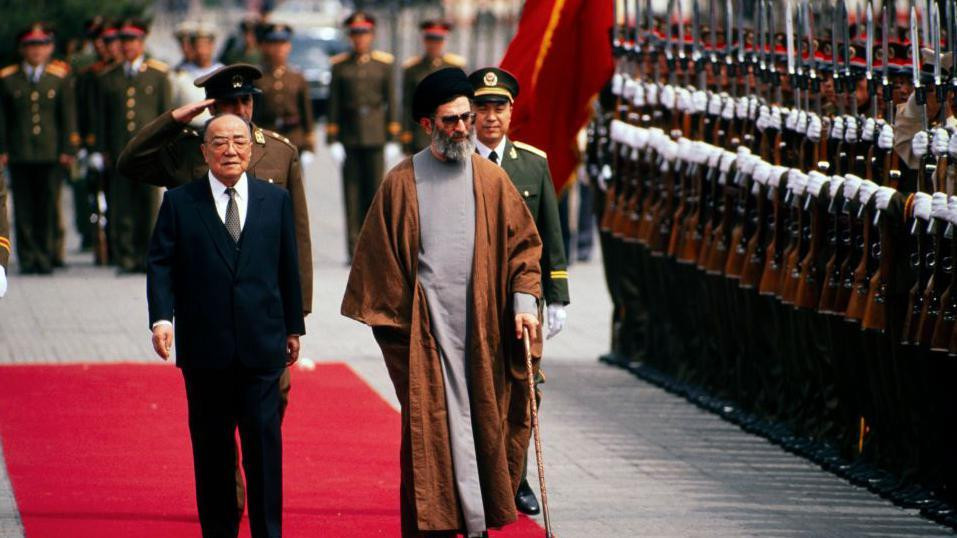 Kineski predsednik Jang Šangkun (1907 - 1998) (u centru levo) i iranski predsednik Ali Hamnei (u centru desno) šetaju zajedno tokom ceremonije dobrodošlice za njegovu državnu posetu, Peking, Kina, 11. maja 1989.