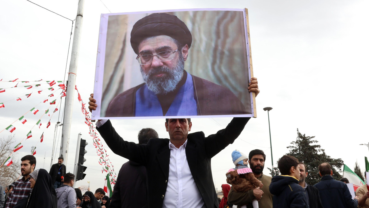 Iranac, u crnom sakou i beloj košulji, drži sliku Modžtabe Hamneija, dok učestvuje u proslavi 47. godišnjice Islamske revolucije u Teheranu 11. februara 2026. godine.
