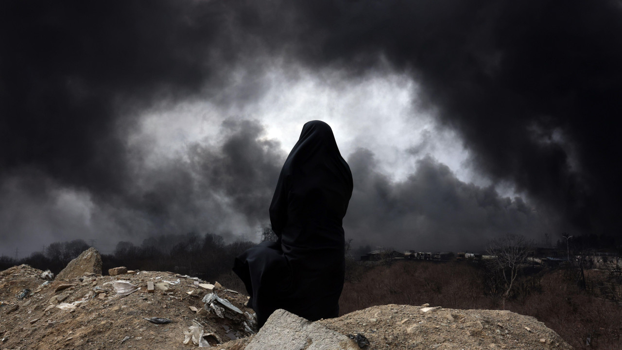 Iranka sa velom, članica iranskog Crvenog polumeseca, posmatra dim koji se i dalje diže iz rafinerije nafte Šahran posle vazdušnog napada u Teheranu, Iran, 8. marta 2026.
