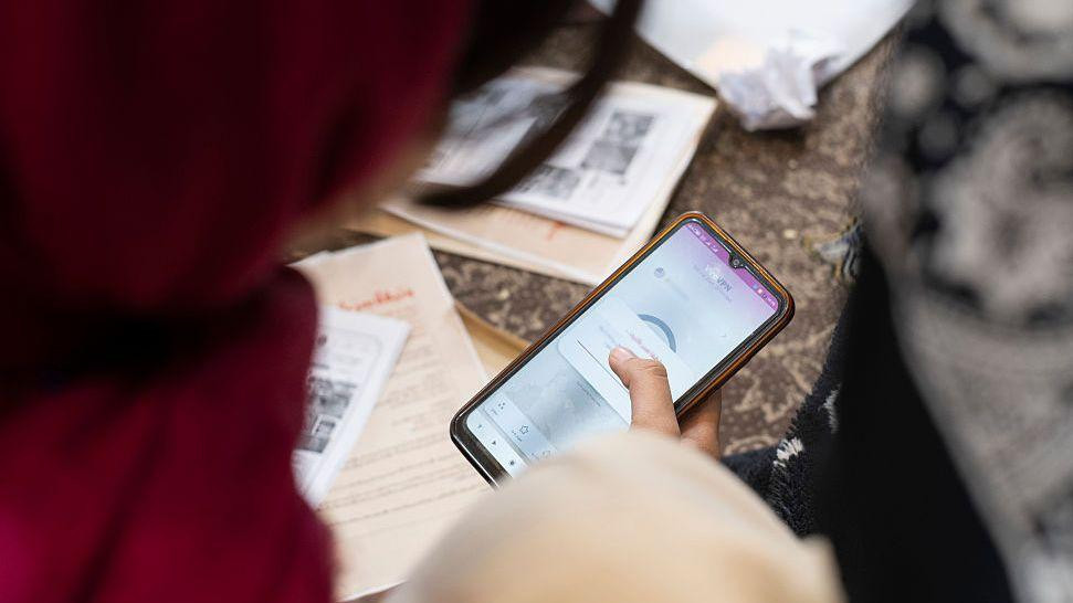 žena sa crvenim šalom gleda u telefon na VPN-u