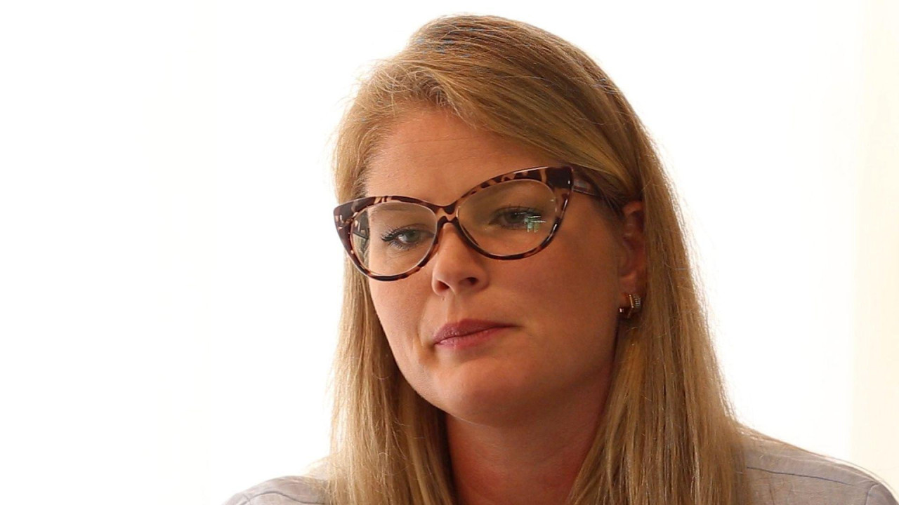 Žena duge plave kose nosi naočare za vid i gleda ka podu 