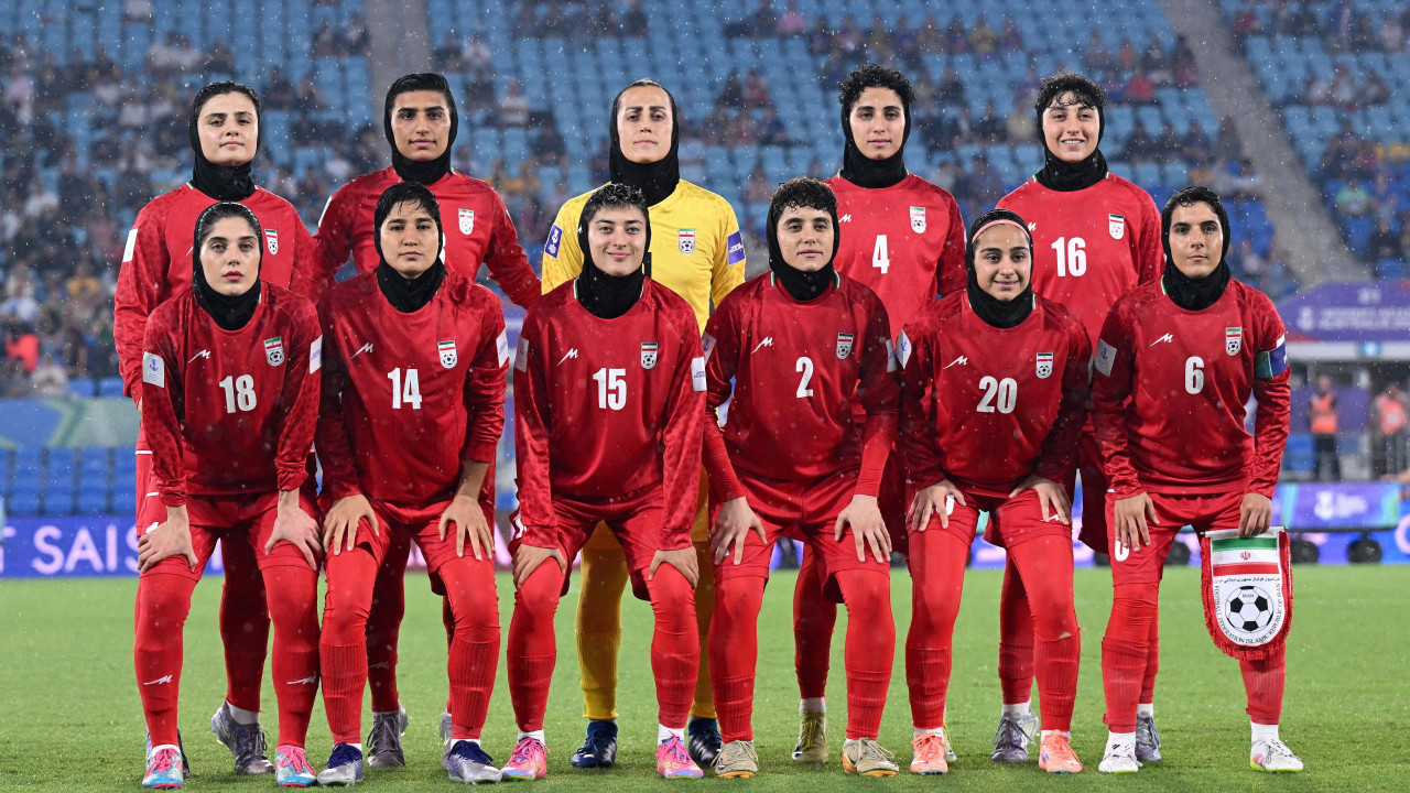 
                    Eleven members of the Iranian women's football team pose for photo on the pitch of the Gold Coast stadium before the 8 March match against the Philippines. They are stand