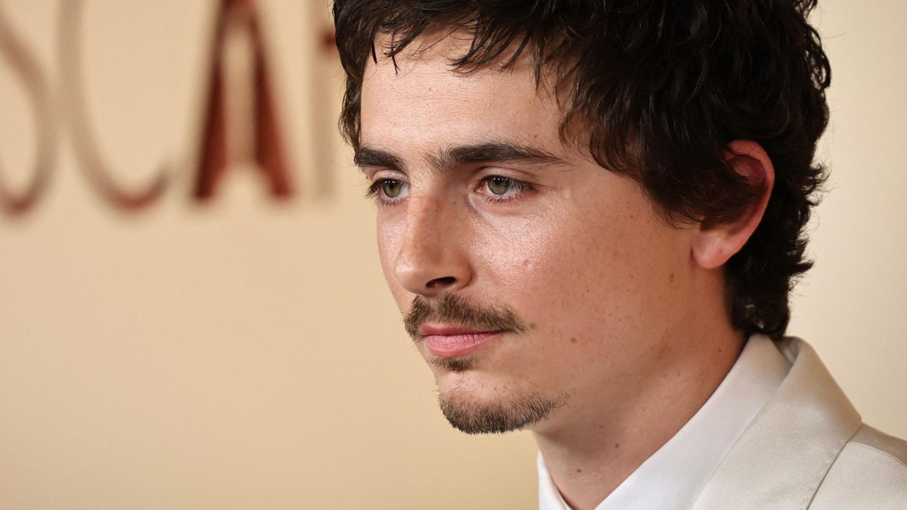 Timoti Šalame u belom odelu gleda sa strane 