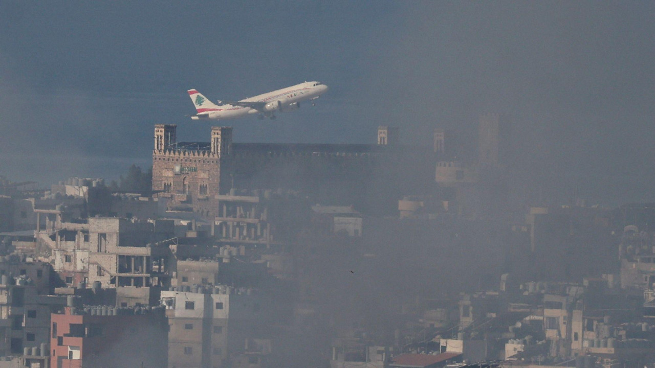 avion poleće iznad Bejruta dok je u toku napad, ispod se vidi dim iznad zgrada