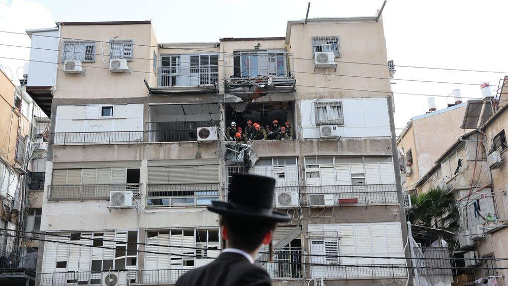 čovek gleda u zgradu pogođenu u iranskom napadu