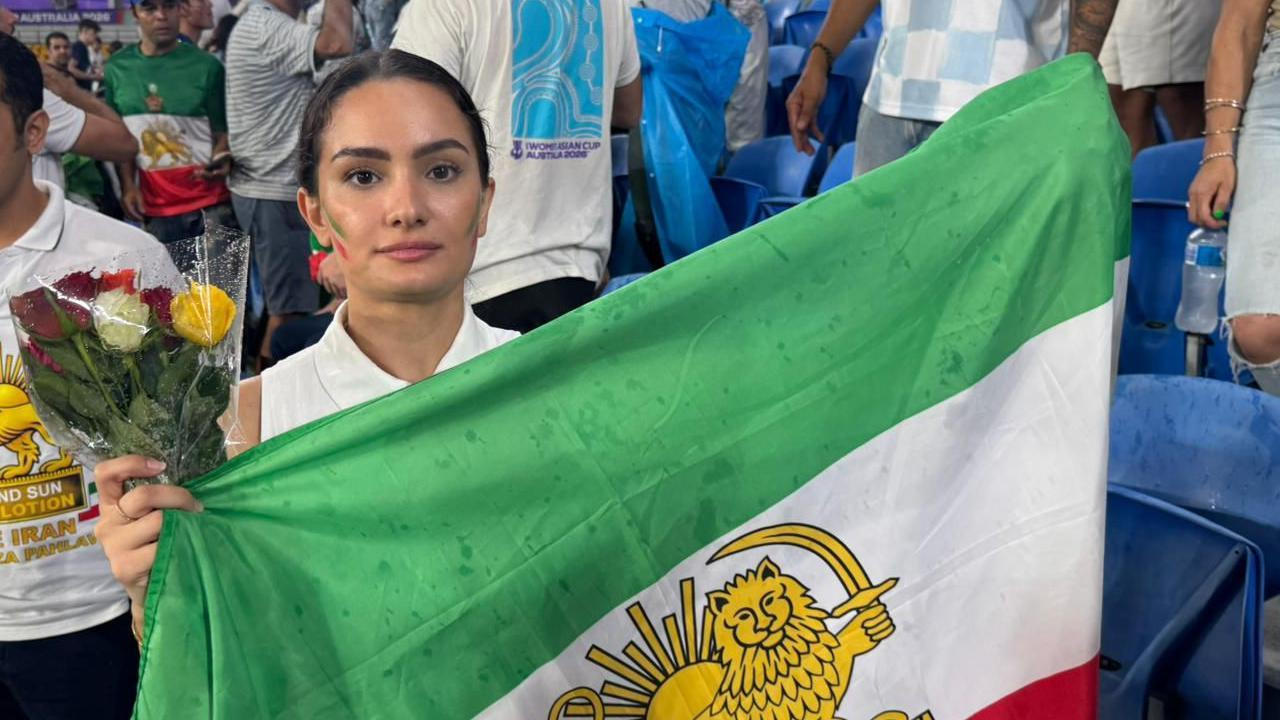 Mlada žena drži buket ruža i iransku zeleno-belo-crvenu zastavu sa suncem i lavom 