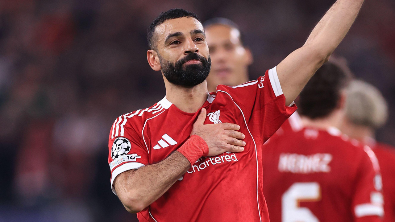 Napadač Liverpula Muhamed Salah maše navijačima dok jednom rukom dok drži grb Liverpula 