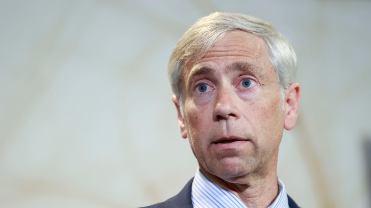 Beri Polak nosi teget odelo, plavo-belu prugastu košulju i plavu kravatu sa sitnim tačkicama.