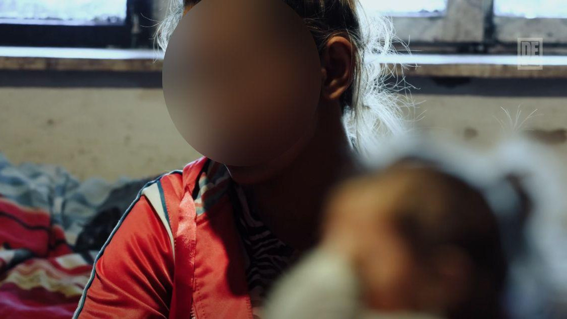 žena drži bebu u naručju, njihova lica su blurovana 