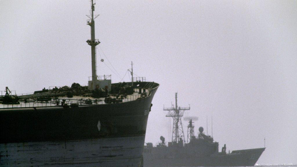 Američki ratni brod u pozadini putuje pored teretnog broda tokom operacije 'Iskrena namera' u Ormuskom moreuzu.