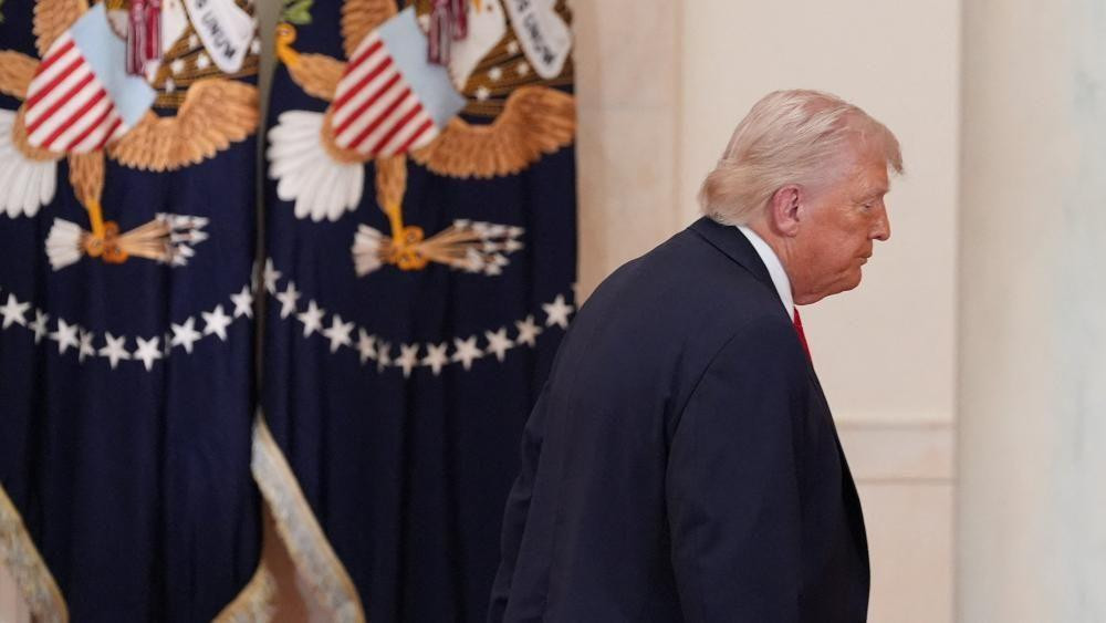 američki predsednik donald tramp, Tramp hoda udesno i dalje od kamere. Sa leve strane su dve američke zastave