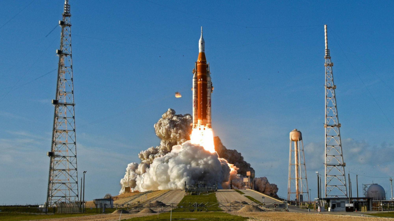 Rocket taking off with bright blue sky behind it.