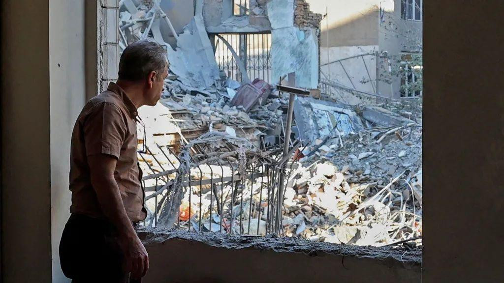 čovek gleda kroz razrušenu zgradu u teheranu