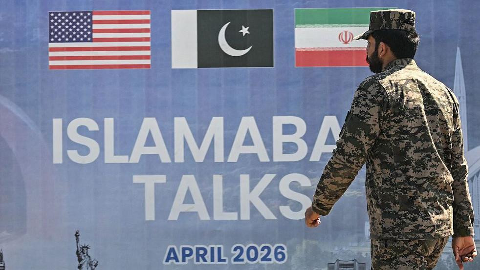 Pakistanski rendžer u kamuflažnoj uniformi prolazi pored bilborda koji najavljuje američko-iranske mirovne pregovore u Islamabadu