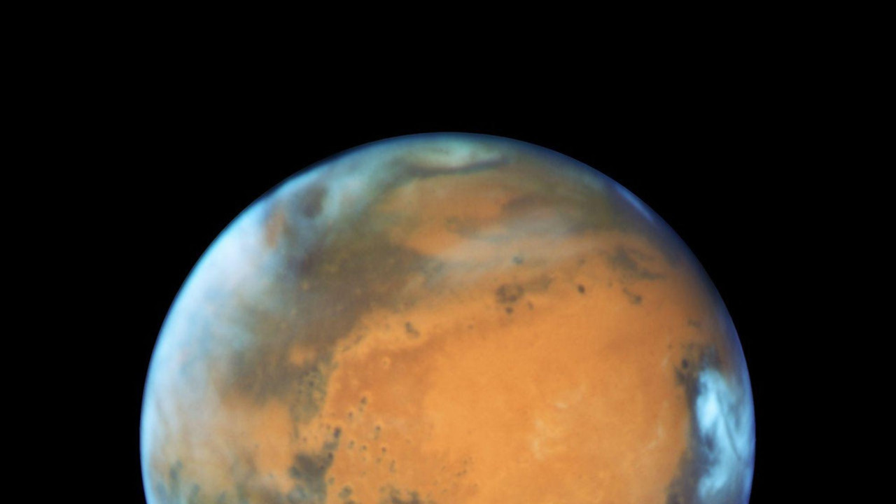 Prikaz Marsa, planete narandžaste planete, sa jarko belim oblacima blizu njene gornje i desne ivice